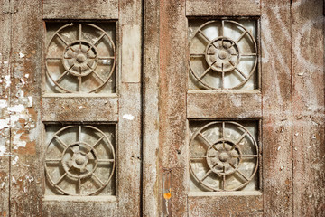 Old brown wooden painted door with four windows and round-shaped metal grid