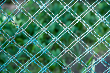 Fototapeta premium Light green old weathered painted mesh fence detail (selected focus)