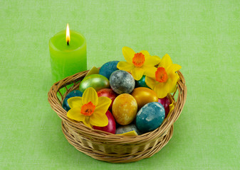 Obraz na płótnie Canvas Easter, colored painted eggs in a wicker basket with moss, daffodils and candle