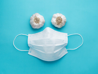 Face of medical mask and garlic on blue background. Concept of protection against coronavirus and...