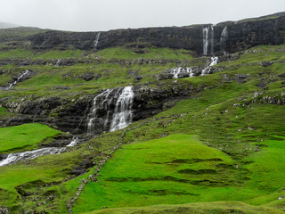 Fototapeta na wymiar Faroe Islands is the land of the waterfalls which cut green fields and falling into the ocean.