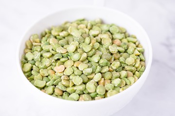 Dry split light green peas in a white cup