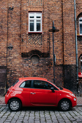 Fototapeta na wymiar Red car fiat 500 on the bricks wall