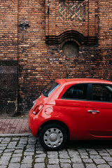 Red car fiat 500 on the bricks wall - obrazy, fototapety, plakaty