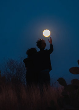 Pareja abraz&aacute;ndose al anochecer frente a la luna
