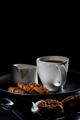 cup of coffee, chocolate candies and cookies on table
