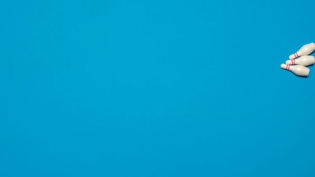 Stop motion animation of a bowling ball striking bowling pins for a strike knocking down all the pins on a blue background