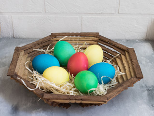 Colored easter eggs in a wooden plate on the table