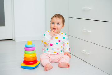 Toddler girl plays educational games at home. Baby sits on the floor of the house