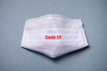 medical protective mask on a blue background with inscription Covid-19, concept accessory for virus protection