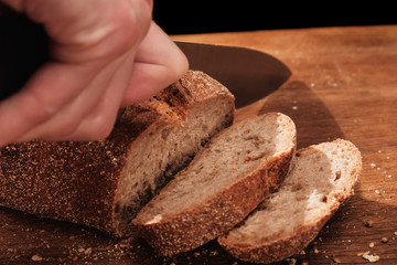 Chef cuts with a knife Whole Fresh fragrant bread on table. Food concept Wheat pastry on cutting board