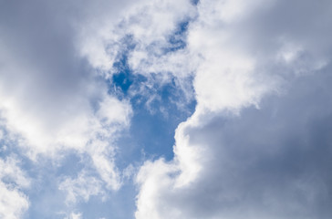 Obraz premium Bright blue sky peeks through the white cumulus clouds on a sunny day.