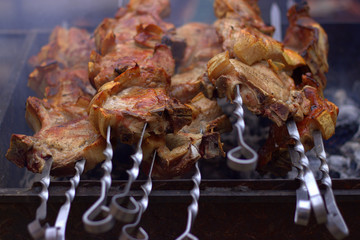  Several skewers with pork entrecotes lie on a steaming grill