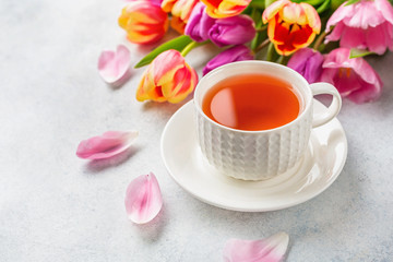 Obraz na płótnie Canvas A cup of tea with tulips on white background