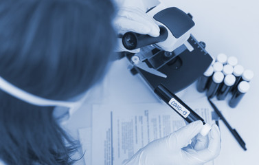 Scientist in laboratory working with microscope. Covid-19 concept.