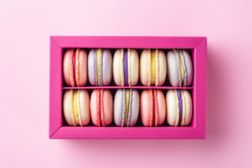 Colorful macaroons and flowers. Sweet macarons in gift box. Top view