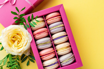 Colorful macaroons and flowers. Sweet macarons in gift box. Top view