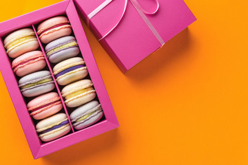 Colorful macaroons and flowers. Sweet macarons in gift box. Top view