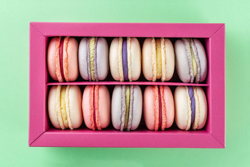 Colorful macaroons and flowers. Sweet macarons in gift box. Top view