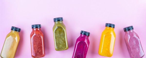 Colourful healthy smoothies and juices in bottles on color background with copy space.