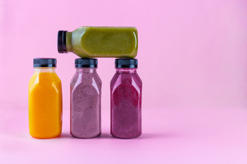 Colourful healthy smoothies and juices in bottles on color background with copy space.