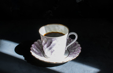 Cup of coffee in a sunbeam against a dark background