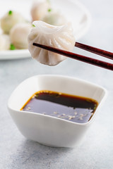 Dumpling being dipped in soy sauce with chopsticks