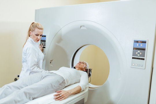 Female senior patient and radiologist during MRI scan procedure at clinic.