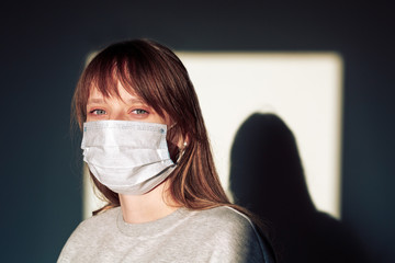 A woman wearing face mask protective for spreading of Coronavirus Disease on the white wall with shadow