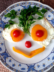 Classic egg breakfast with a smile. Breakfast for the baby. Fried eggs in the form of a smile on a plate of greens