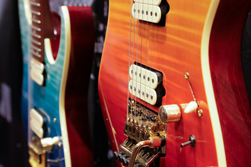 A view of several colorful guitars on display at a local music store, hanging on the wall.
