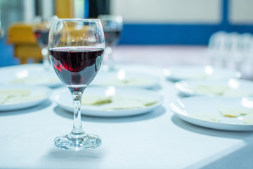 Glass of wine on the table with white tablecloth, in the background dishes with unleavened bread.