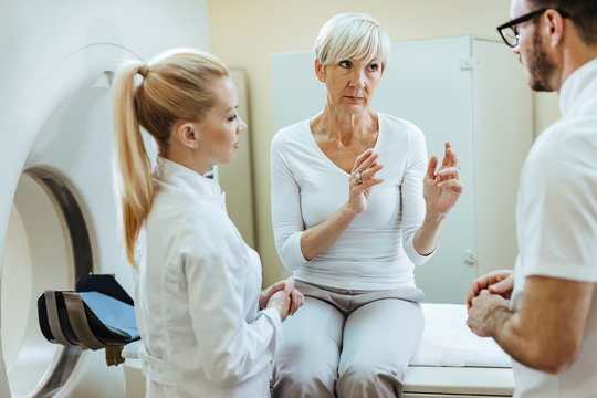 Worried mature woman talking to doctors before MRI scan examination.