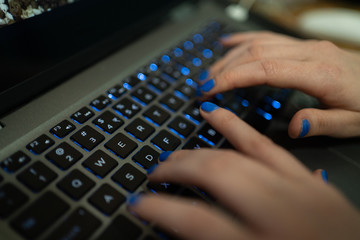 Kobieta pisze maila na klawiaturze laptopa (komputera). Przyciski mają niebieskie podświetlenie - obrazy, fototapety, plakaty