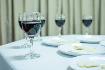 Glass of wine on the table with white tablecloth, in the background dishes with unleavened bread.