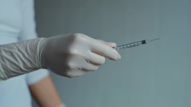 insulin Needle syringe. closeup nurse hands in white sterile protective gloves takes off cap from syringe needle. Tool with needle in hands