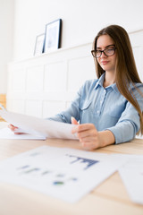 Young girl entrepreneur in glasses is studying the consumer market, and statistics of purchasing power