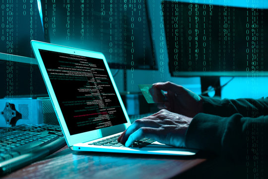Cyber criminal with credit card hacking system at table, digital binary code on background