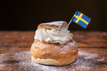 Traditional Scandinavian cream and almond paste filled cardamom bun Semla with a Swedish flag.