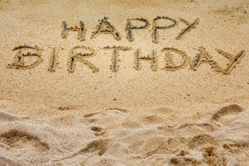 Handwritten  "Happy Birthday" on a sandy beach