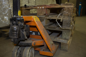 Old hand powered pallet jack with pallet on the floor