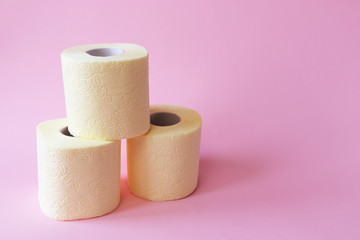 On a pink background, three rolls of toilet paper, the concept of hygiene and panic due to lack of...