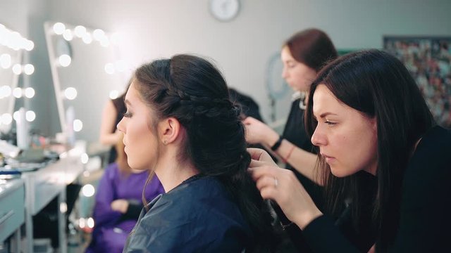 Hairdresser creating complicated hairstyles at barbershop salon. Beauty and haircare concept