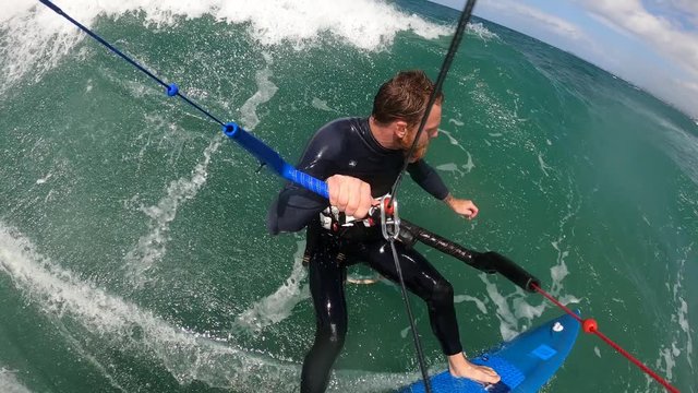bearded kitesurfer riding the wave