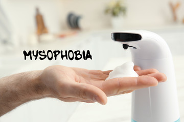 Man using automatic soap dispenser indoors, closeup. Mysophobia