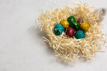 On a gray background straw with easter eggs, horizontal orientation