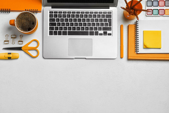 Flat lay composition with modern laptop and orange stationery on white table
