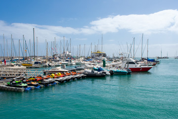 Fototapeta na wymiar Corralejo, Fuerteventura, Canary Islands, Spain: Boats and Yachts in Corralejo Port, calm ocean water 