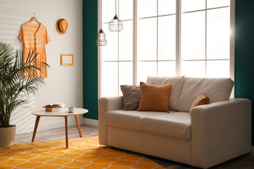 Stylish room interior with comfortable sofa and orange carpet