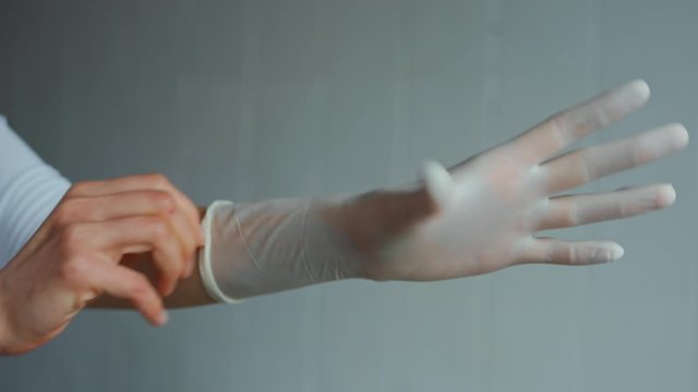 medic in a hospital ward puts on sterile protective gloves on white background